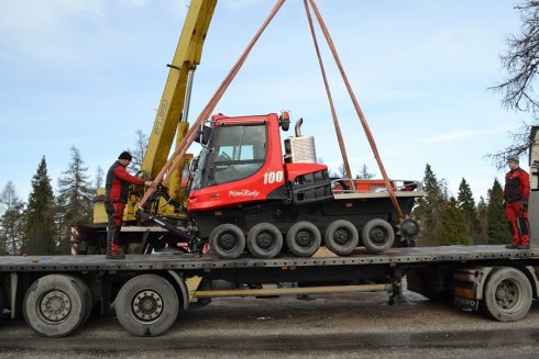 Rolba opúšťa príves kamiónu. Na vykládku dohliadajú mechanici TopKarMoto SK, Robo a Ivan.